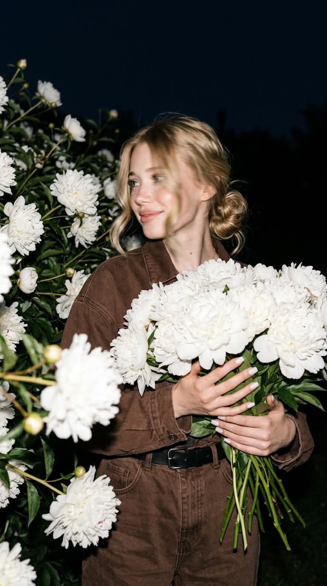 A candid nighttime editorial portrait of a young blonde w...